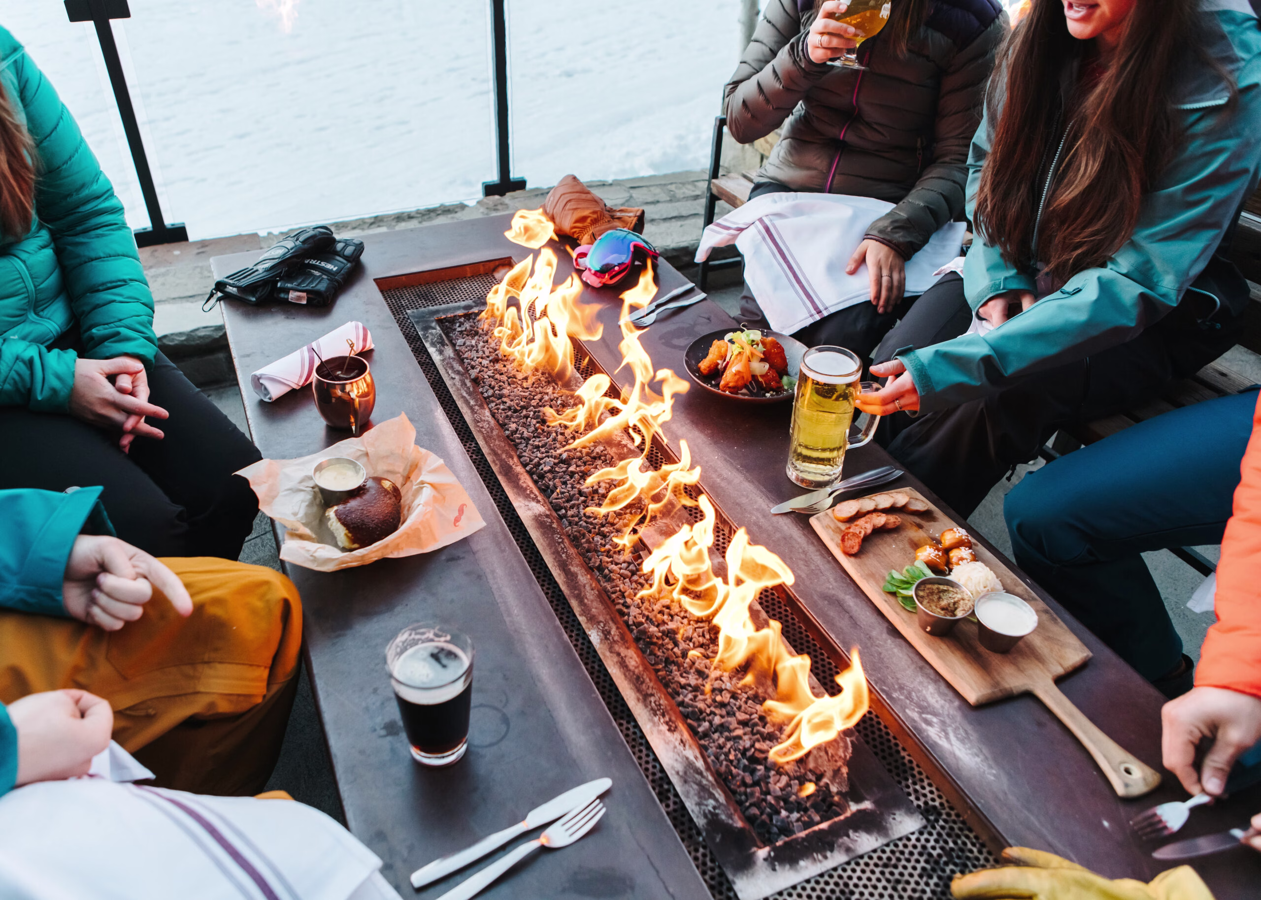 Friends enjoy outdoor dining in Jackson Hole, Wyoming, by a fire pit. Membru connects tourists with local businesses for unique experiences.