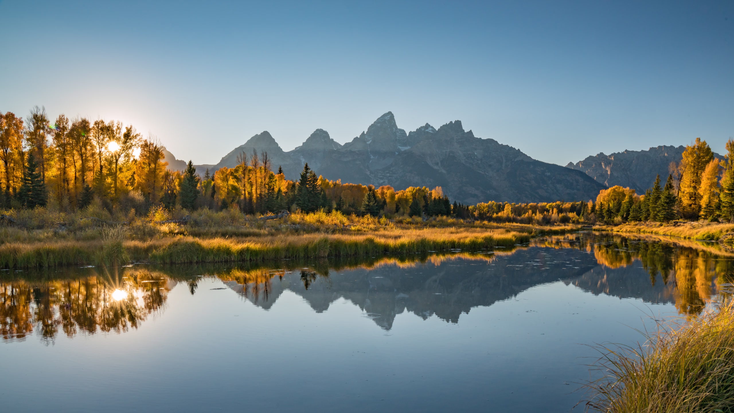 Connection and contemplation in Jackson Hole, Wyoming: Couple enjoying breathtaking mountain scenery beside a peaceful lake. Get inspired to visit Jackson Hole and create unforgettable memories