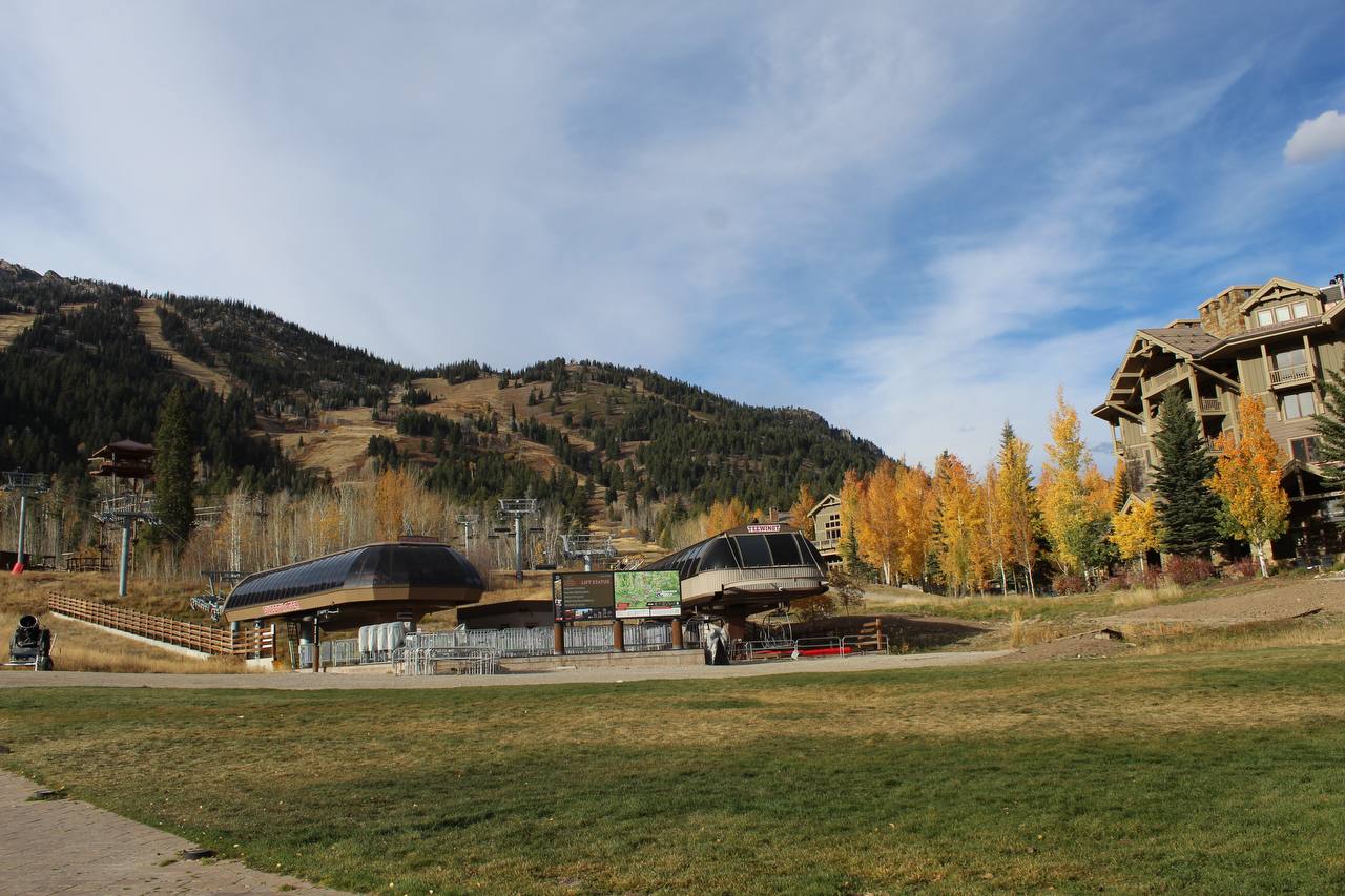 A ski lift station with gondolas at the base of a mountain with ski slopes and colorful autumn trees in Jackson Hole, Wyoming